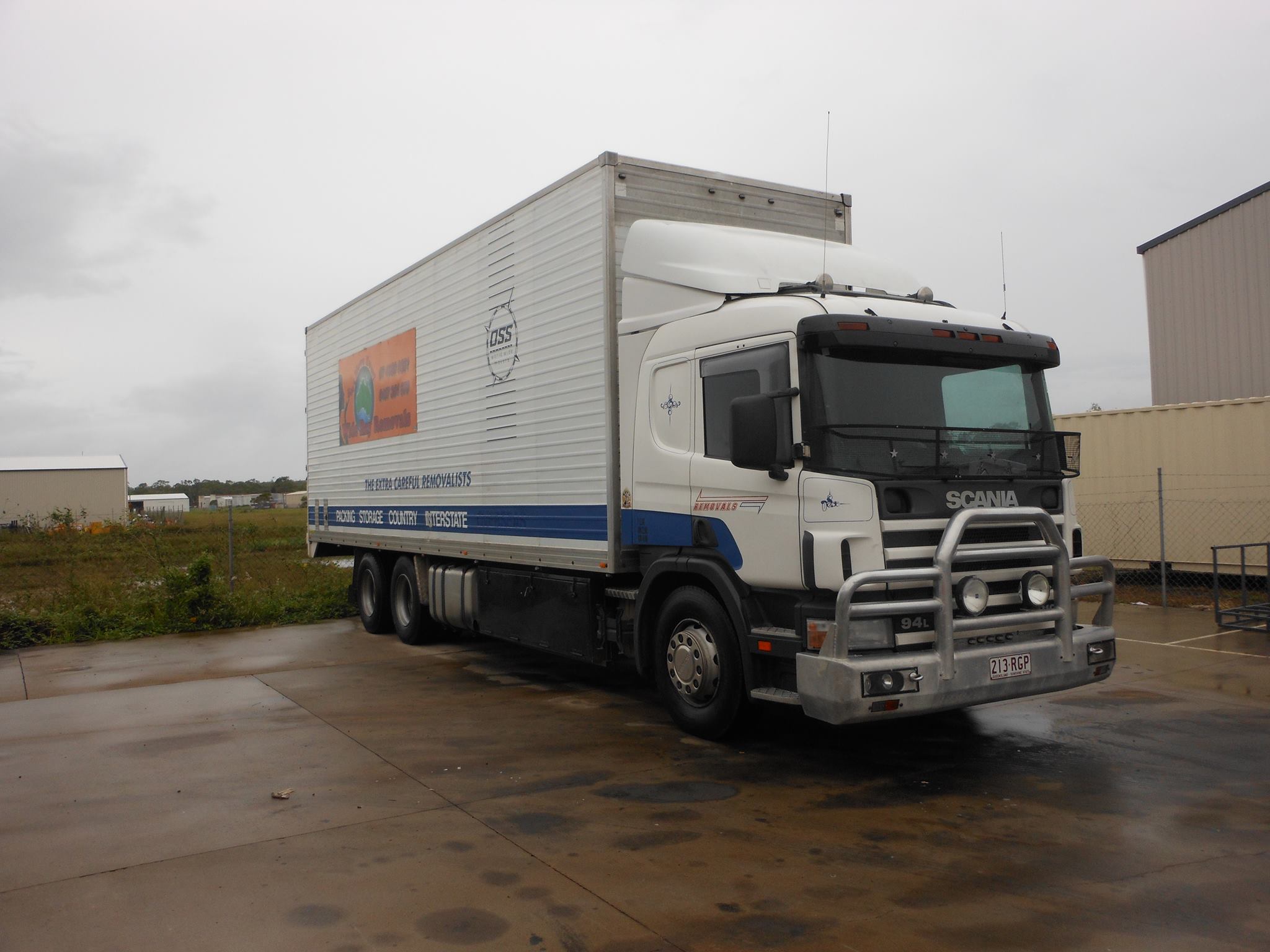 Signwritten Scania removals truck parked in a yard on an overcast day