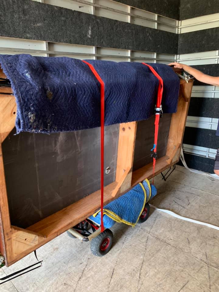 Large timber furniture piece wrapped in a blanket and strapped to a trolley