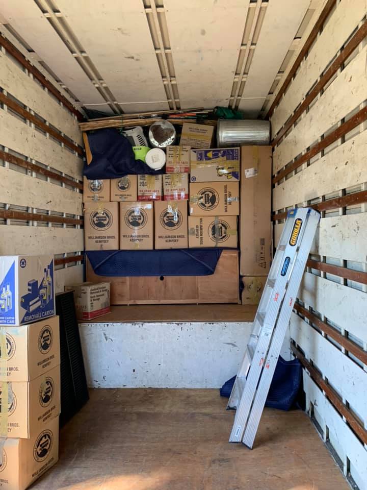 Removals truck loaded with stacked boxes, with a ladder against the side wall