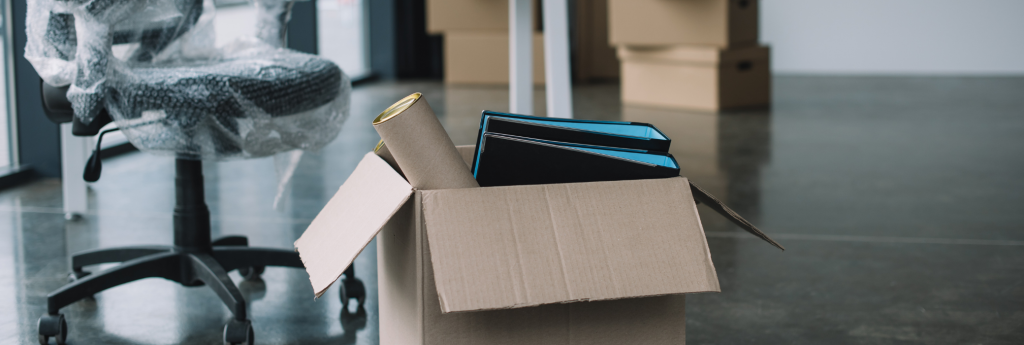 Office chair wrapped in plastic beside a box of folders ready to move
